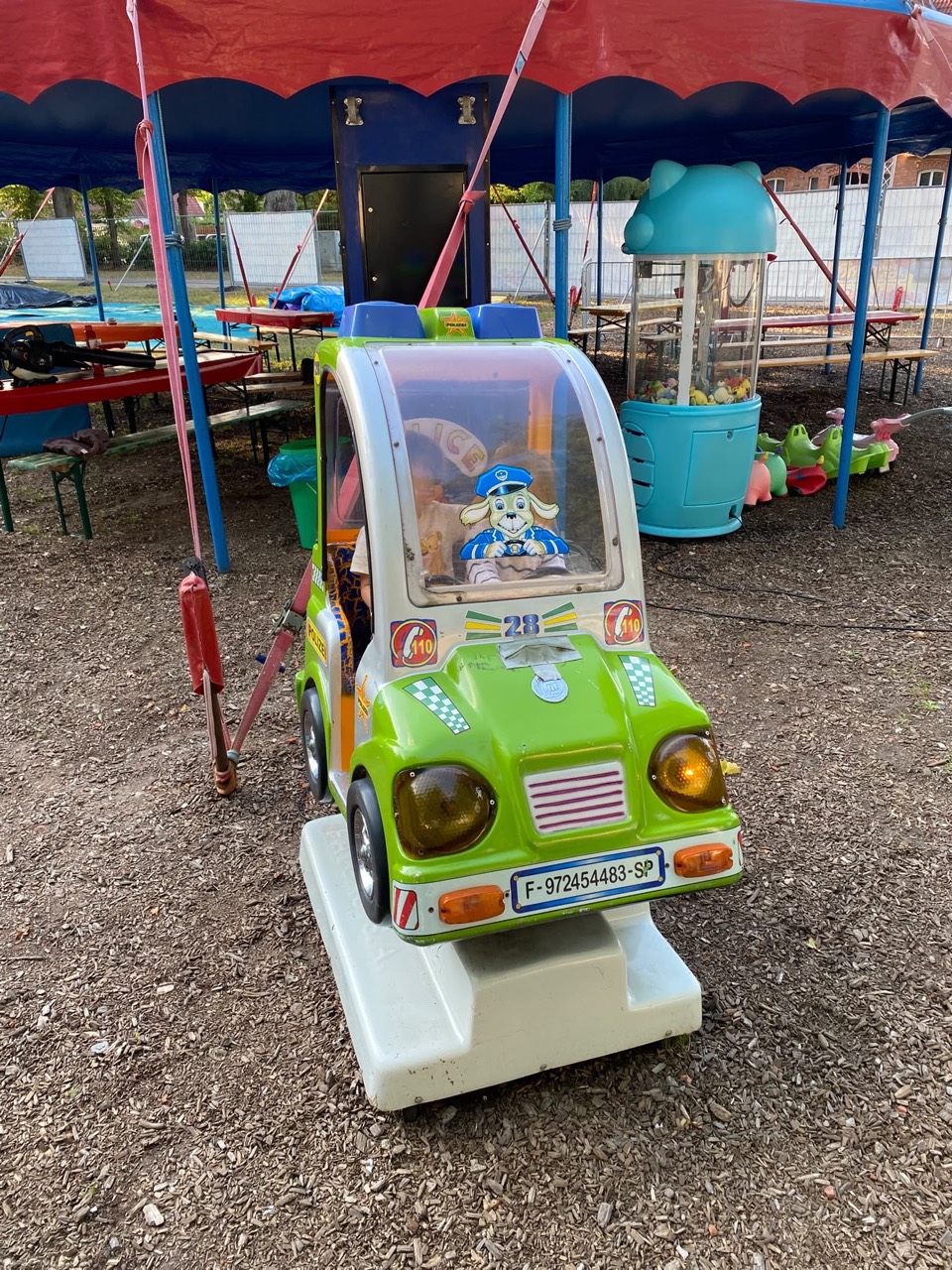 Grünes Kinderfahrgeschäft in Form eines Autos unter einem Zelt